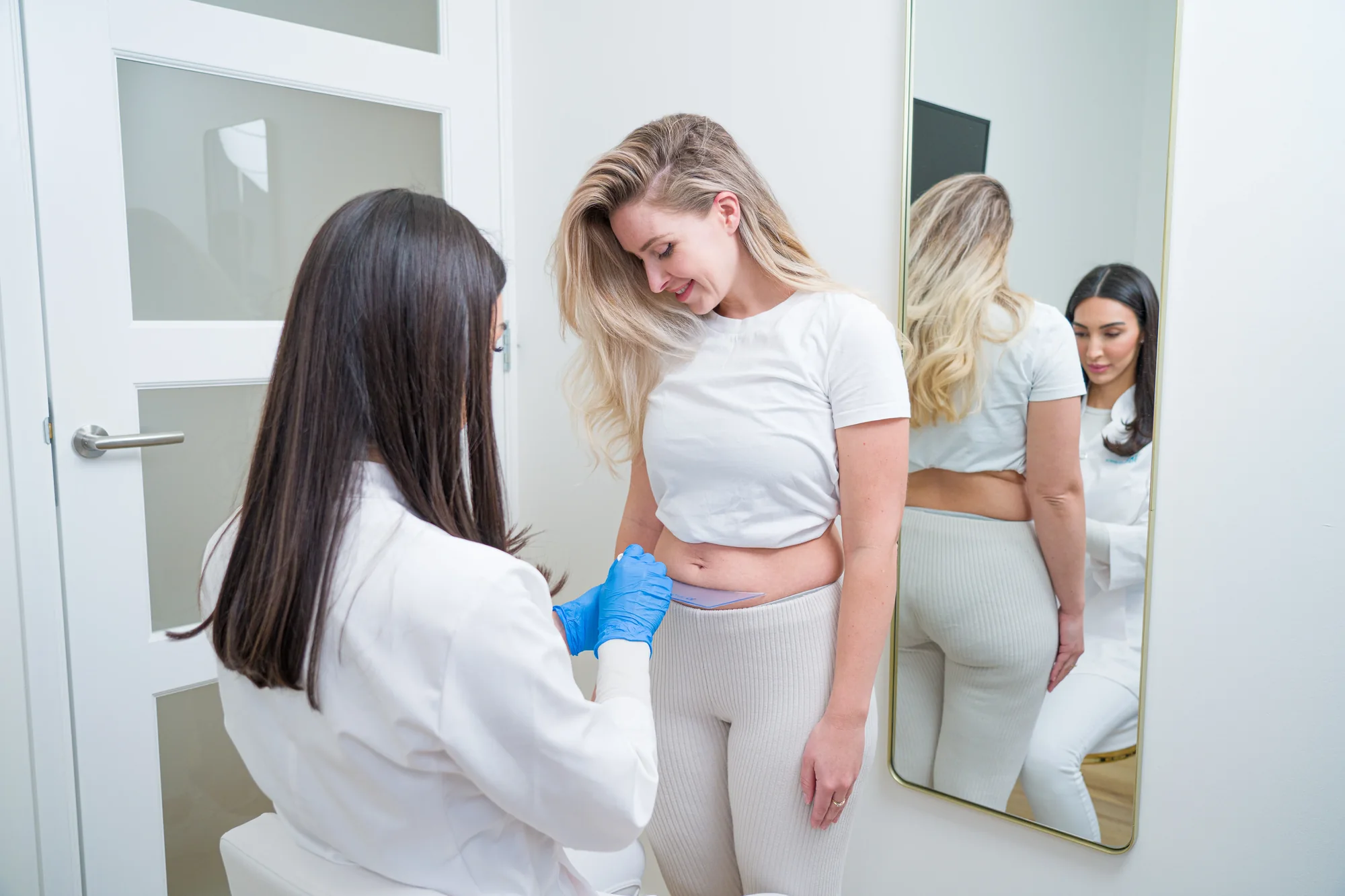 Specialist bespreekt de buikzone met een client voor de spiegel