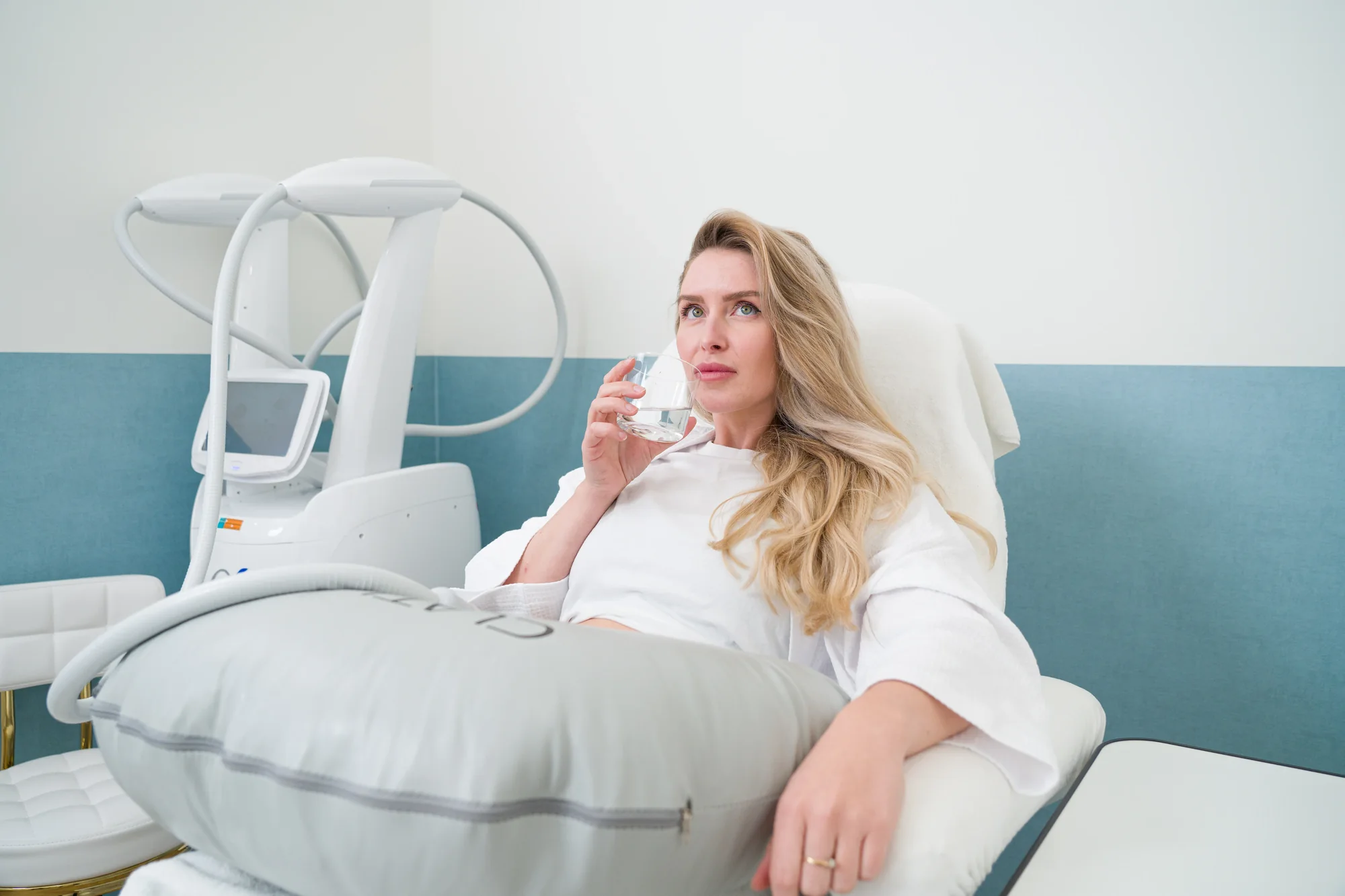Client drinkt water tijdens de vet bevriezen behandeling van de buik